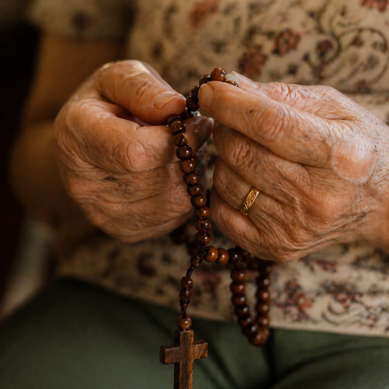 Mãos segurando terço de madeira em oração